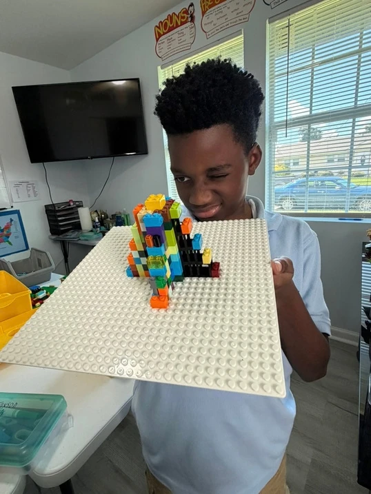 A student holds a model Mayan pyramid